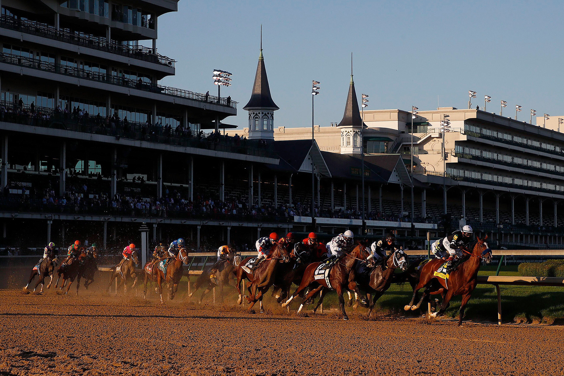 Horses racing in the Kentucky Derby beneath the twin spires of Churchill Downs
