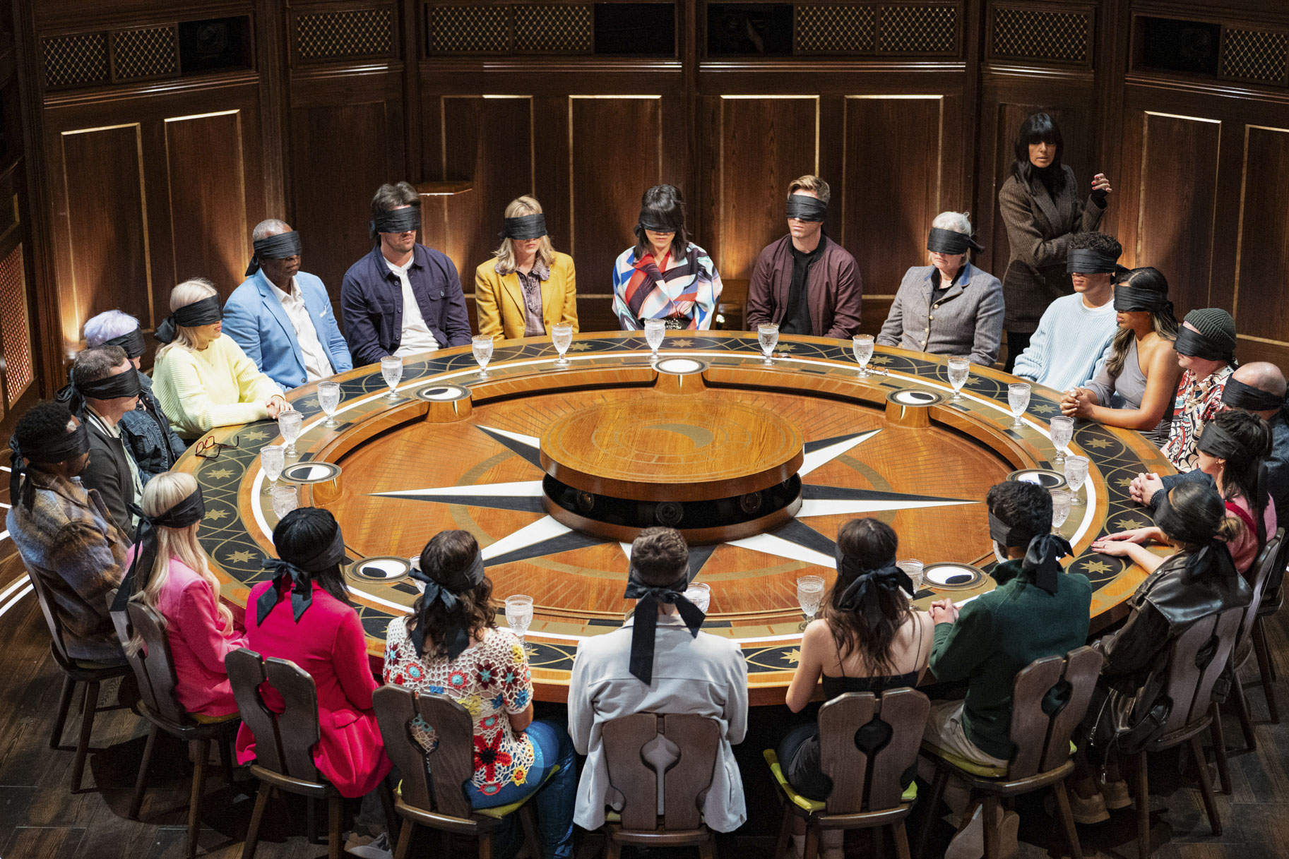 The blindfolded cast of The Traitors UK Season 3 Epsiode 1 sitting at the roundtable.