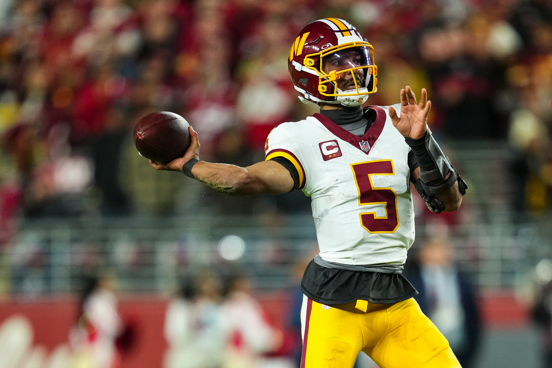 Jayden Daniels throws a football while wearing a Washington Commanders uniform during a game against the San Francisco 49ers.