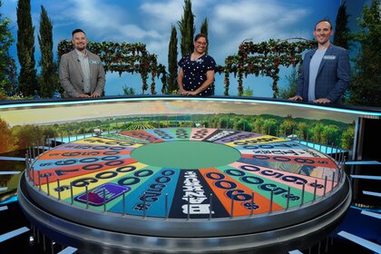 Contestants smile next to the wheel on The Wheel of Fortune Season 43.