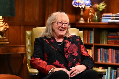 Donna Kelce wears a red patterned blazer and sits in an armchair on The Traitors Episode 401.