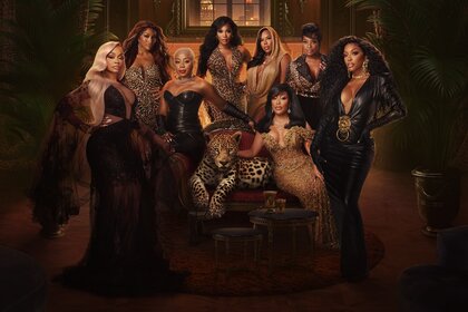 The full RHOA cast standing in an ornate room with brown decor.