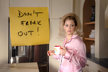 Elizabeth Banks wearing a pink pajama top and holding a mug of coffee on The Miniature Wife.