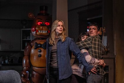 Toy Freddy peaking around the corner while Vanessa, Abby, and Mike hide in&nbsp;Five Nights at Freddy's 2 (2025).