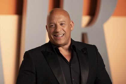 Vin Diesel smiling in front of a step and repeat.