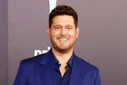 Michael Bublé smiling and posing in a blue suit at the 61st Academy Of Country Music Awards.