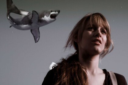 A shark flying in the air while Claudia looks on in Sharknado (2013).