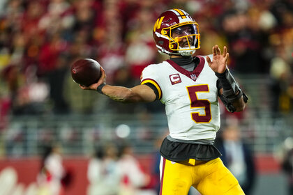 Jayden Daniels throws a football while wearing a Washington Commanders uniform during a game against the San Francisco 49ers.