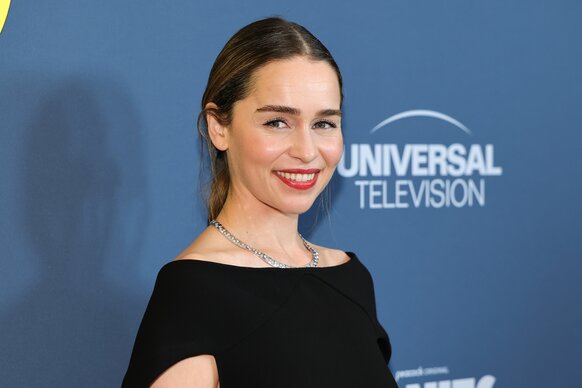 Emilia Clarke smiles in a black top.