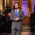 Harry Styles in a gray suit on stage during the monologue on Saturday Night Live Season 51 Episode 15.