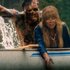 Linda Cardellini as Pam Voorhees reaches over the side of a canoe as a burned figure rises from the water behind the canoe.