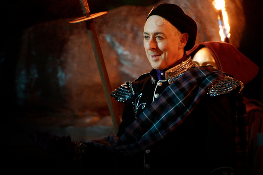 Alan Cumming stands in front of a fire on The Traitors Season 4.