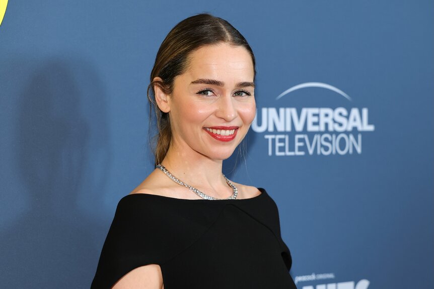 Emilia Clarke smiles in a black top.