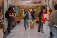 John (Max Burkholder) and Ted (Seth MacFarlane) running down a school hallway in Ted Season 2.