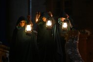 Candiace Dillard Bassett, Lisa Rinna, and Rob Rausch stand in hoods while holding lanterns on The Traitors Episode 401.