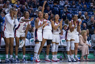 The Connecticut Huskies players cheer on the sidelines of a basketball game.