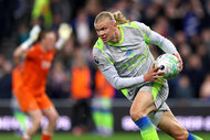 Erling Haaland holding a soccer ball while running on a soccer field.