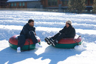 Jeremiah Brown and Andreina Santos on floting tubes on the snow.