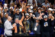 New York Knicks cheering while owner James Dolan is interviewed by Ernie Johnson Jr. after his team's victory against the San Antonio Spurs in Game Five of the 2026 NBA Finals.