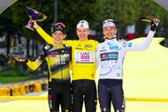 Jonas Vingegaard, Tadej Pogacar, and Florian Lipowitz celebrating and holding trophies at the Tour de France 2025.