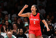 Angel Reese of the Atlanta Dream raises a fist and shouts while wearing a red No. 5 jersey during a game against the New York Liberty.