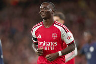 Bukayo Saka smiles while jogging in an Arsenal jersey during a UEFA Champions League match against LOSC Lille.