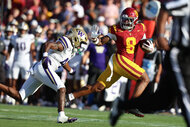King Miller #8 of the USC Trojans runs with the football as a Washington Huskies defender reaches out during a college football game.