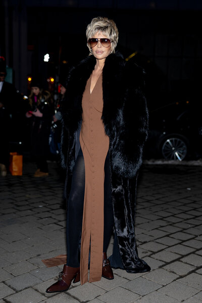 A full length of Lisa Rinna wearing a brown floor length dress and a fur coat.