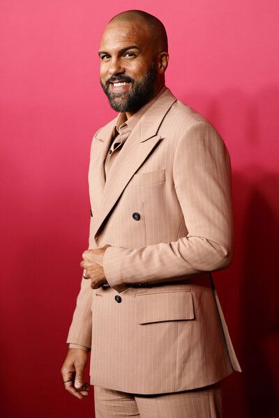 O-T Fagbenle smiling in front of a step and repeat.