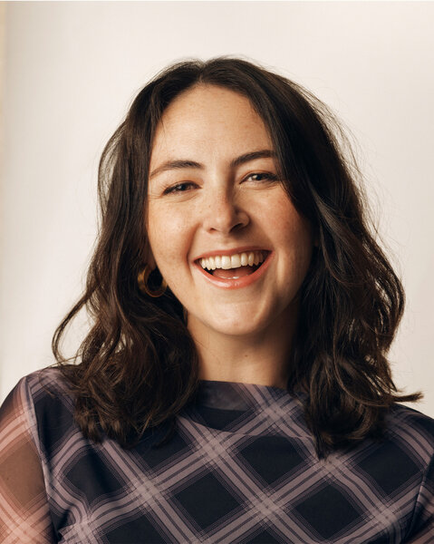 Emma Sidi posing in front of a cream backdrop.
