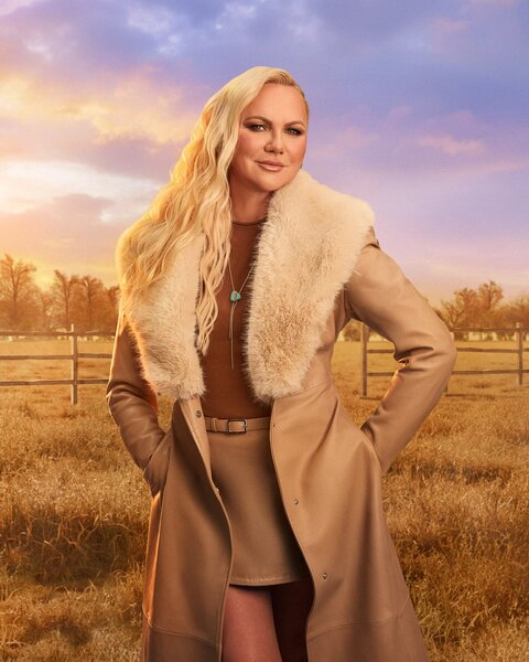 Galyna Saltkovska standing in front of a farm field, trees, and dusk skies.