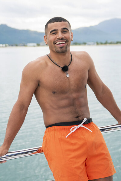 Ronnie Gunter wearing neon orange swim trunks and smiling on a boat in Love Island USA Season 8.