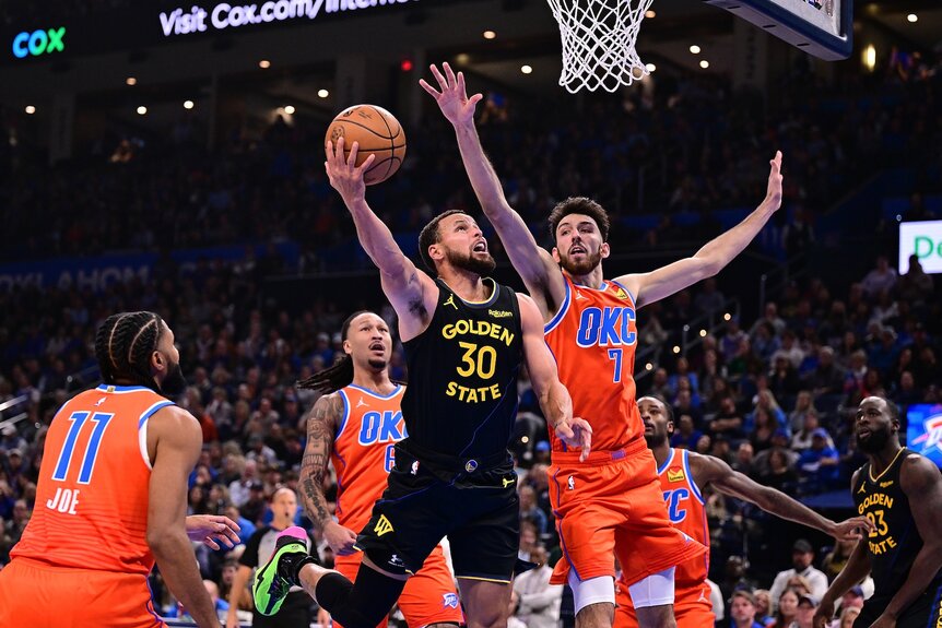 Stephen Curry #30 of the Golden State Warriors attempts a shot in front of Chet Holmgren #7 of the Oklahoma City Thunder.