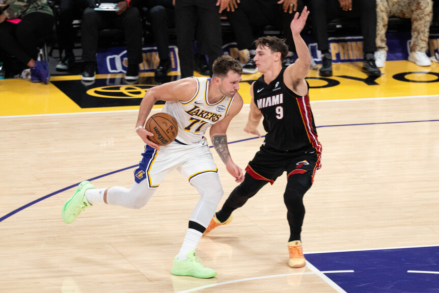 Luka Doncic dribbling on the court against a Miami Heat player