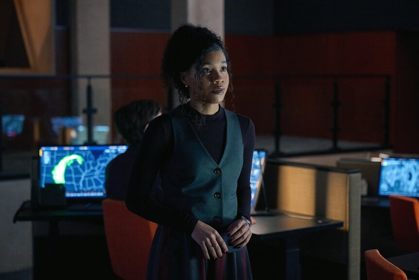 Parker (Sinclair Daniel) stands in an office full of computers on The Copenhagen Test Season 1.