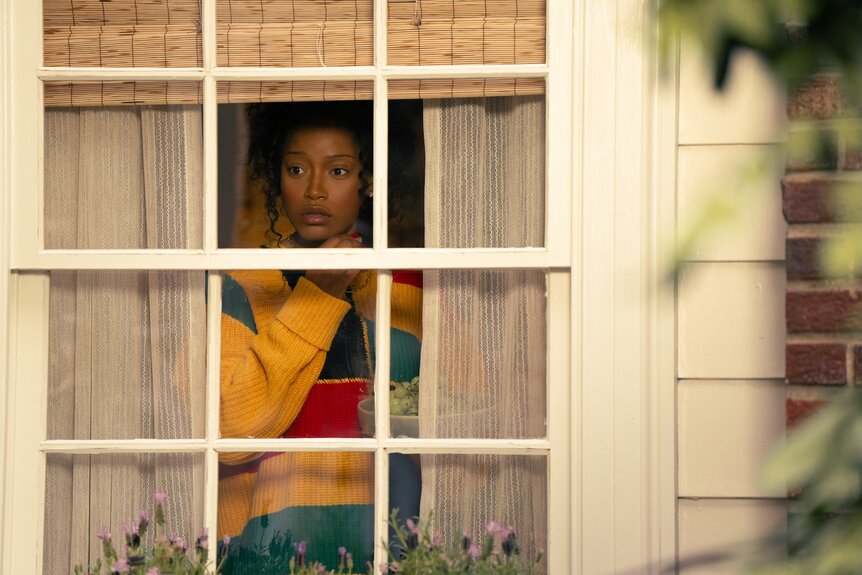 Samira (Keke Palmer) ppeeks through a window on The 'Burbs Season 1.