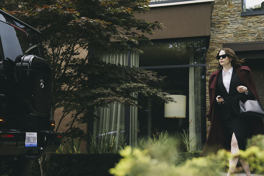 Michelle (Emma Stone) walking outdoors to a car in Bugonia (2025).