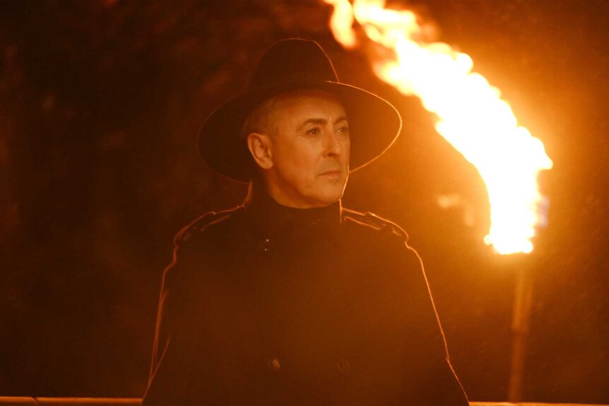 Alan Cumming holding a stick of fire on The Traitors Season 4 Episode 6.