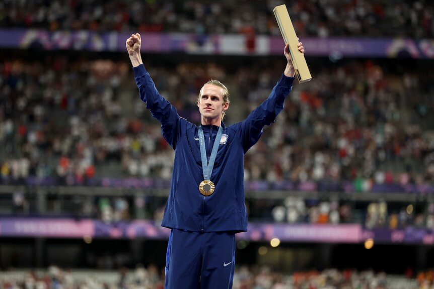 Cole Hocker raises his arms at the podium with gold at the Olympic Games Paris 2024.