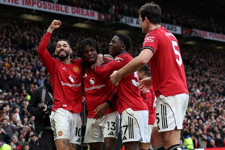 Manchester United players celebrate with teammates during a match.