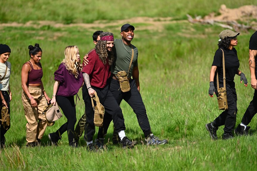 ​​​​​​​The cast of The Traitors marches through a green field on The Traitors Episode 404.