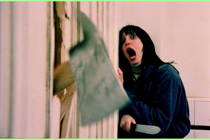 Wendy Torrance (Shelley Duvall) screams as an axe breaks through a door on The Shining (1980).