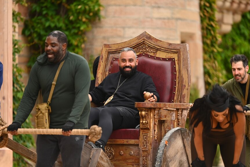 Ron Funches drags Yamil “Yam Yam” Arocho in a rickshaw on The Traitors Episode 402.