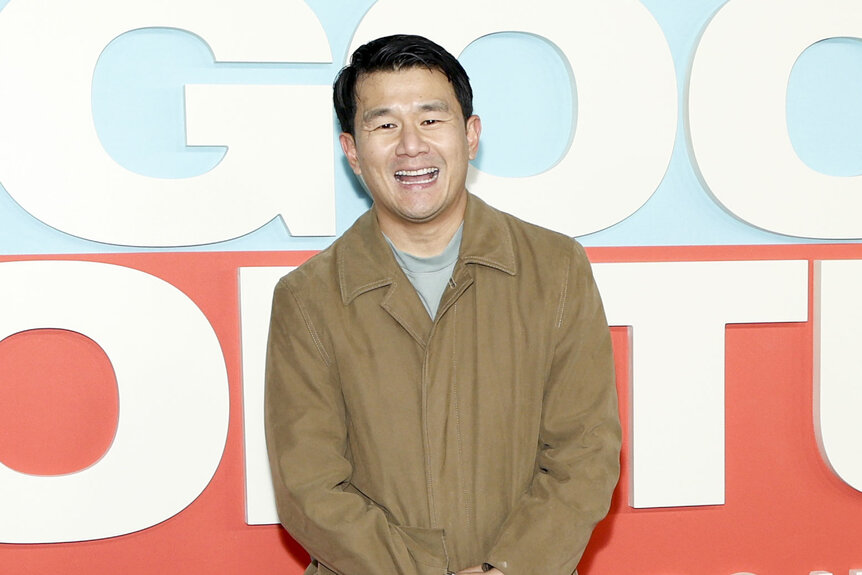 Ronny Chieng smiling in front of a step and repeat.