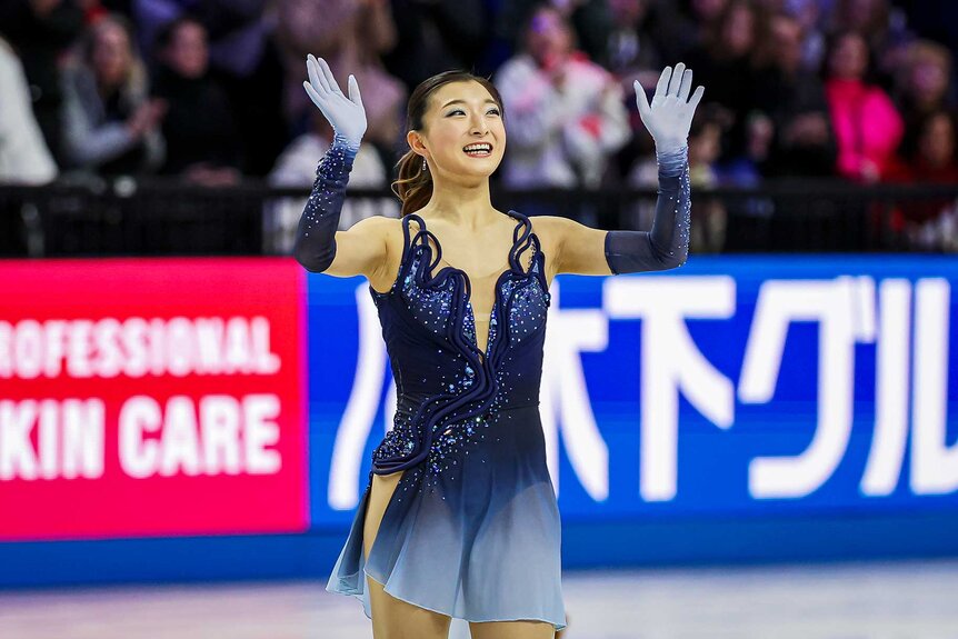 Kaori Sakamoto of Japan smiling and waving in the Women's Short Program during the ISU World Figure Skating Championships.