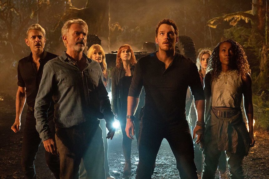 Dr. Ian Malcolm,&nbsp;Dr. Alan Grant,&nbsp;Dr. Ellie Sattler,&nbsp;Claire Dearing,&nbsp;Owen Grady,&nbsp;Maisie Lockwood, and&nbsp;Kayla Watts standing together in a dimly lit room in&nbsp;Jurassic World Dominion (2022).
