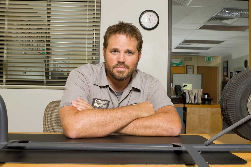 Roy sitting at a desk with his arms folded in The Office Season 3.