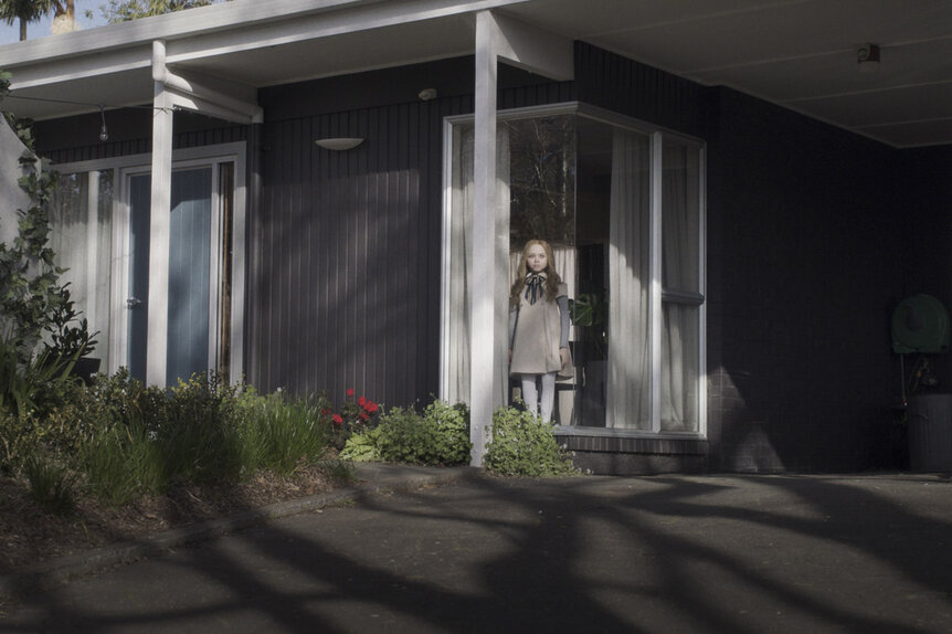 M3GAN looking out of a window.