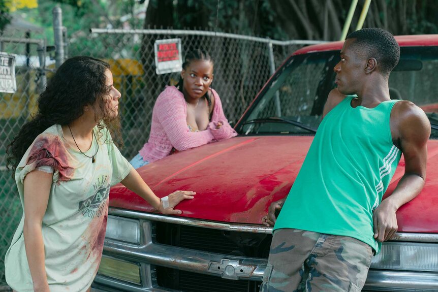 Etta, Lovely, and Stanley talking around a car in M.I.A. Season 1 Episode 2.