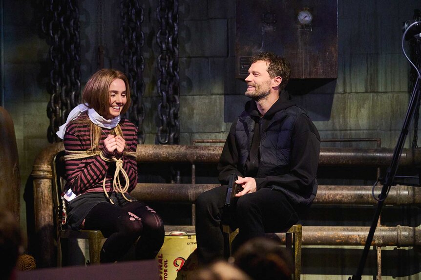 Jamie Dornan holding a gun during a sketch on Saturday Night Live UK Show 2.